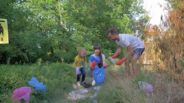 Stop plastic, jonge moeder en vader met kleine dochter geeft om ecologie natuur en het verzamelen van polyethyleen afval in vuilniszak tijdens het reinigen van vervuiling — Stockvideo