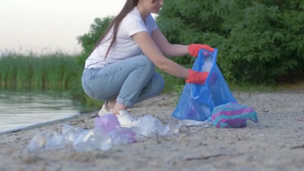 Környezetvédelem, aktivista nő gumikesztyűben gyűjti műanyag és polietilén alom szemeteszsákban, miközben a part tisztítása — Stock videók