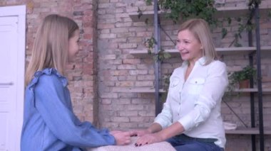 Anne-çocuk ilişkisi, mutlu küçük kız annesine sırlarını anlatıyor. El ele tutuşuyor ve evde dinlenirken gülümsüyor.