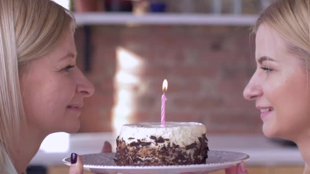 Vœu d'anniversaire, maman souriante avec fille adulte soufflant des bougies sur le gâteau de vacances et souriant et regardez-vous — Video