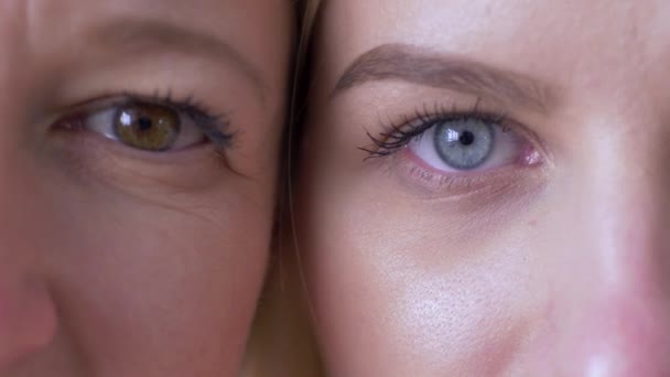 Generation difference, eyes of mum and daughter faces next to one another looking together at camera — Stock Video