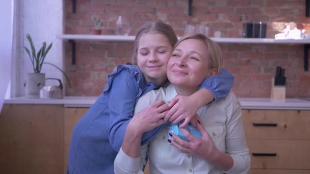 Geschenk an Mutti, kleines Mädchen schenkt Mutter für den Urlaub und umarmt sie zu Hause sanft und Mutti überrascht — Stockvideo