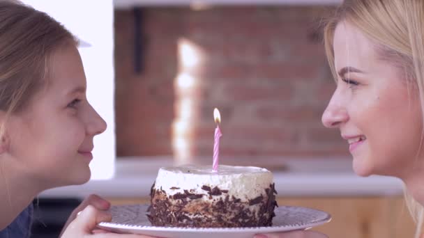 С днем рождения мама, молодая мама с ребенком девочка задувая свечи на торт и улыбается и смотреть друг на друга — стоковое видео