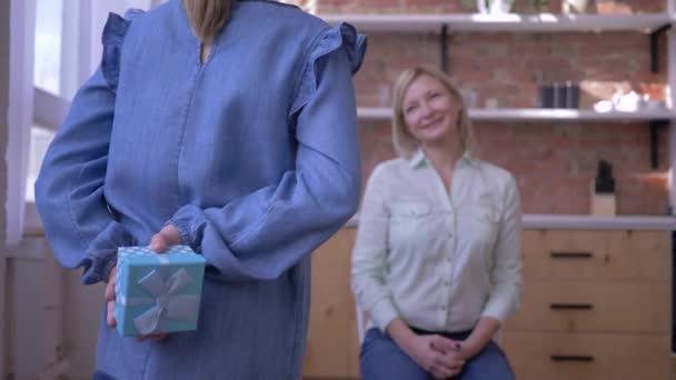 Szczęśliwego Dnia Matki, Kochające małe dziecko córka gratuluje uroczej mamie i daje pudełko prezentów i przytula czule w pokoju domowym — Wideo stockowe