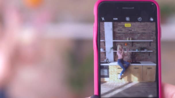 Foto en el teléfono móvil, joven mujer divertida posando para la fotografía en el teléfono inteligente de cerca en la cocina — Vídeos de Stock