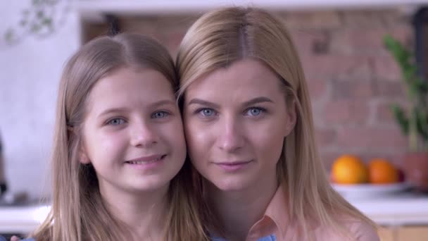 Portret van zorgzame zussen, mooie kleine en volwassen meisjes met blauwe ogen glimlachen en kijken thuis naar de camera — Stockvideo