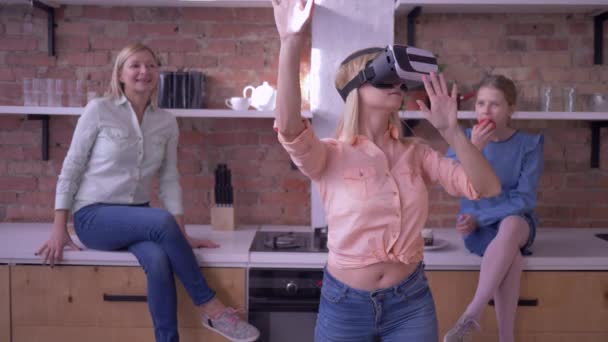 Tecnología VR, hembra joven en casco de realidad virtual juega juego moderno con la familia en la cocina — Vídeo de stock