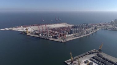 Deniz kıyısında konteynırları ve vinçleri olan sanayi iskelesi.
