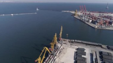 Deniz limanı panoramasında konteynırlarla dron görüntüsü ve deniz kıyısında vinçleri kaldırma