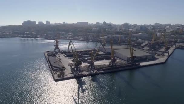 Верхний вид торгового морского пирса с контейнерами и подъёмными кранами на морской набережной против города — стоковое видео
