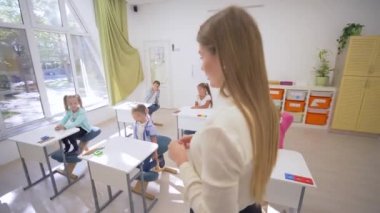 Öğretmen bayan, okuldaki eğitim dersinde küçük şirin çocuklarla sıralarda etkileşim halindedir.