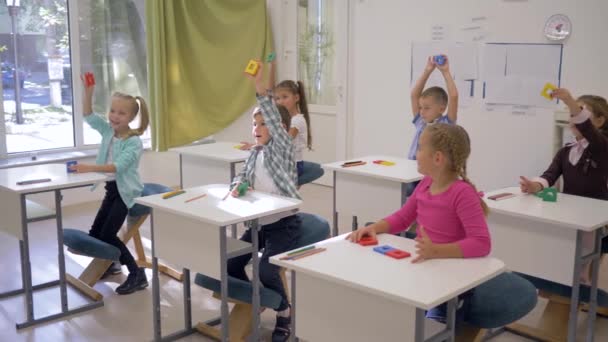 Educación preescolar, niños felices inteligentes levantan formas geométricas en la mano durante la lección — Vídeos de Stock