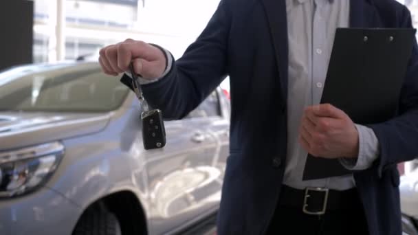 Centro di vendita auto, venditore di auto professionale ragazzo tiene in mano le chiavi della nuova automobile in vendita in concessionaria — Video Stock