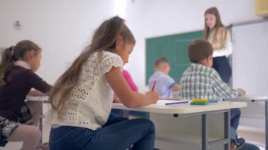 İlköğretim okulundaki eğitim dersi sırasında masadaki güzel öğrenci portresi. Odaklanmamış geçmiş üzerine.