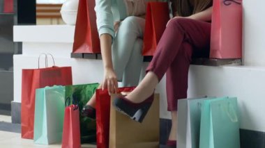 Alışveriş satışları, kadın arkadaşlar indirimli sezonda şık ayakkabılar giyerek bacaklara yakın paketlere alışveriş yapmayı düşünüyorlar.