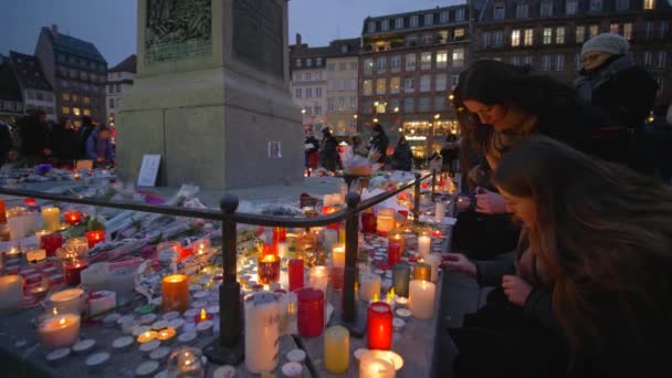 Memorial terrorist attack, mourners girls set fire to candles in memory of victims Terrorism and military actions on place of death of people on eve Christmas at European city street — Stock Video