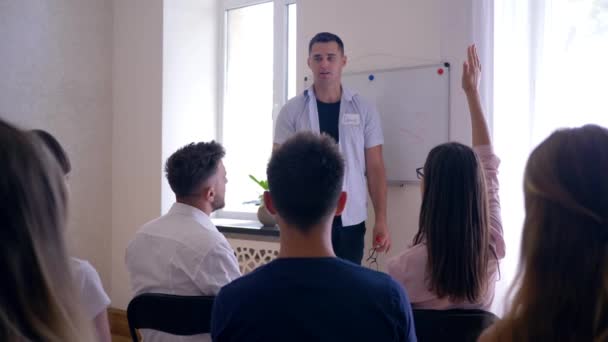 Mitarbeiterschulung, erfolgreiche Leute heben die Hände, um ihre Gedanken mit Trainer und Publikum auf einem Seminar zu teilen — Stockvideo