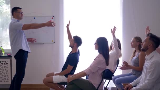 Teamtraining, Referent stellt neuen Businessplan auf Whiteboard vor und glückliches junges Mädchen stellt Fragen auf Seminar — Stockvideo