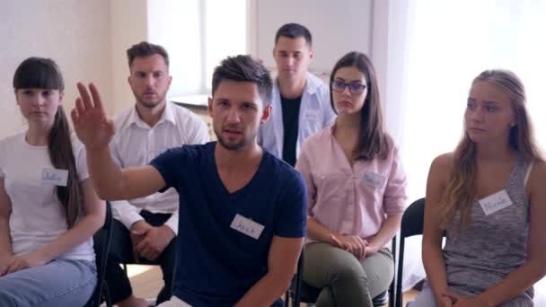 Группа поддержки, молодой застенчивый мужчина говорит о проблемах на психотерапии обучения — стоковое видео