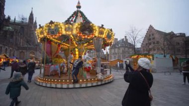 Turist kasabasında şenlik havası, çocukların Noel atlıkarıncaları ve turistler şehir meydanında cep telefonuyla fotoğraf çekiliyor.