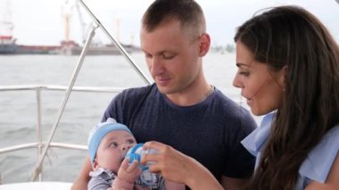 Çocuk elinde ilk meyvesini yiyor baba, tatilde bebeği olan aile, denizde ebeveynler ve çocuklar, yatta mutlu çift.