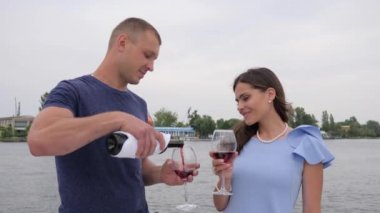 Mutlu çift arka planda kırmızı bir yudum içer. Romantik iki insan tatilde. Bardaklar ellerde, erkekler ve kadınlar.