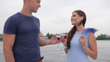 Erkek ve kadın şarap içip yatta öpüşüyor, mutlu çift arka planda kırmızı bir yudum içiyor.