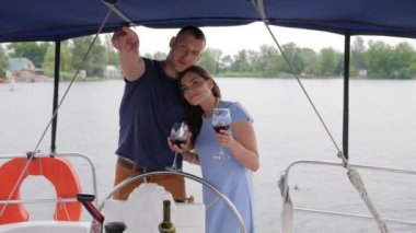 Tatil köyünde iki kişi, mutlu aile çifti yatta şarap içiyor, suda dinleniyor, romantik çift denizde kırmızı içecek içiyor.