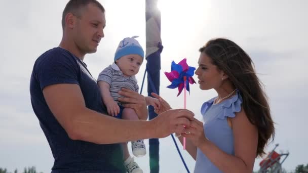 Child in hands of daddy near to mother In sunlight, dad and mom play with son in open air, — Stock Video