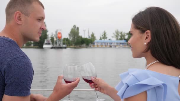 Vila på vatten, man och kvinna dricka vin på yacht, glad par dricka röd dryck i bakgrunden havet — Stockvideo
