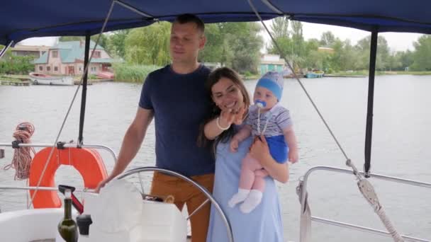 Vidám szülők és a baba hétvégén a háttérben tenger, anya, apa és kisgyermek a nyári szünetben a folyón — Stock videók
