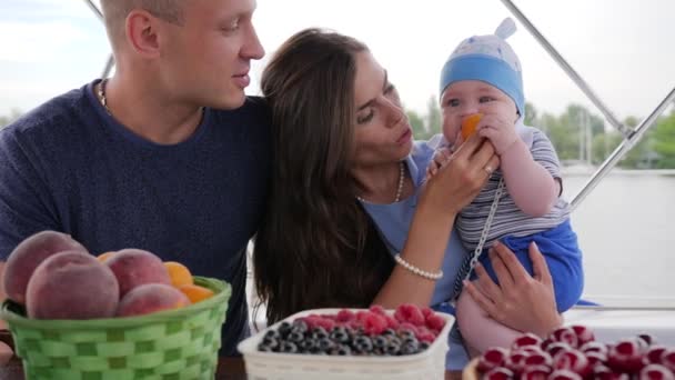 Kid eats first food on hands moms on rest, love couple together with small baby, caring for baby during summer holidays — Stock Video