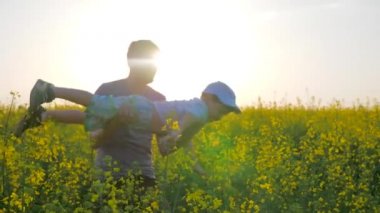 Eldeki küçük çocuk çiçek açmış bir uçak şeklinde babası, kollarında oğlu olan babası çayır çiçeklerinde oynuyordu.,