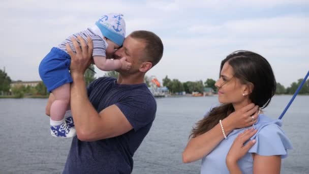 Feliz infancia de los padres amorosos del bebé apagado, descanso del verano de la pareja afortunada con el bebé en el lago , — Vídeos de Stock