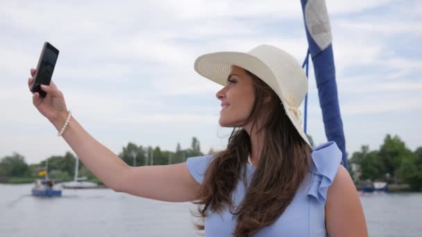 Trevlig flicka gör selfie på yacht, android i handen kvinnor, semester bilder, kvinna gör bilder på din mobiltelefon i det fria — Stockvideo