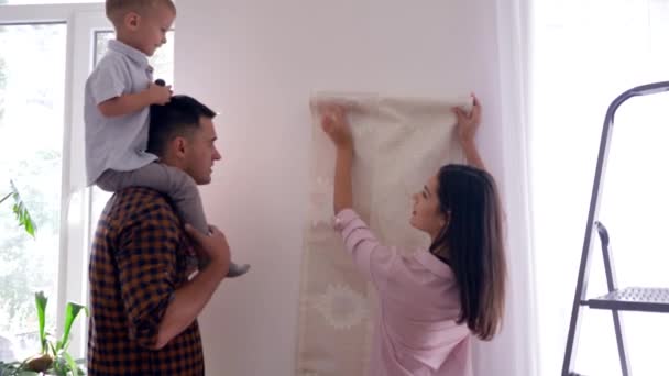 Carte da parati per la casa, bella mamma e papà con bambino sulle spalle fanno riparazioni in casa — Video Stock