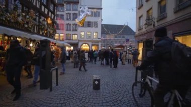 İnsanlar Noel arifesinde sokaklarda tatil için süslenmiş çelenklerle hediyelik eşya dükkanlarının önünden geçiyorlar.