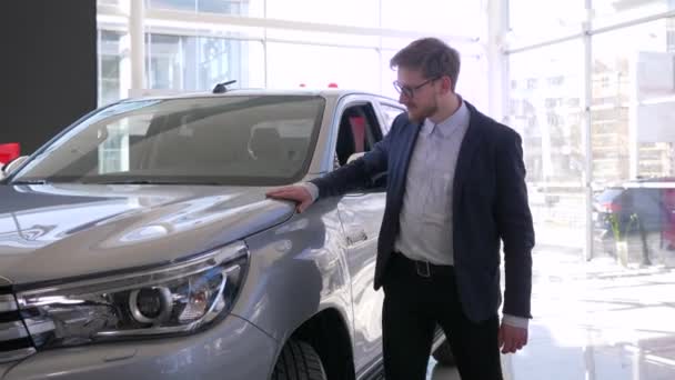 Auto köp, ung köpare man med glasögon gärna stryker ny bil och ger positiv gest — Stockvideo
