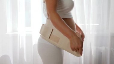 Müstakbel anne hamile kadınlar için bandaj sıkıyor ve ağır çekimde koca göbeğe dokunuyor.