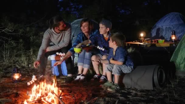 Батьки з дитиною маршмеллоу на багатті в ліс, щаслива сім'я смажить зефір у вогні — стокове відео