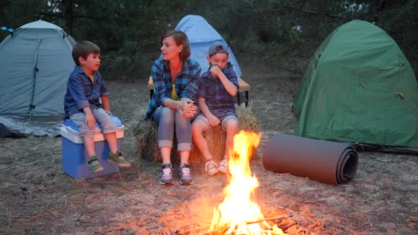 Resa i läger, mor och två barn sitter på halmbalen bredvid baleld, mamma och barn kommunicerar nära brasan — Stockvideo