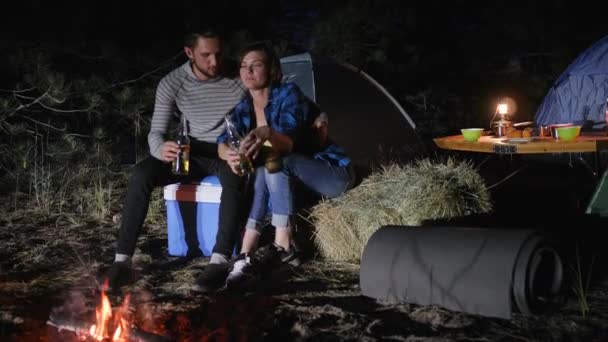 Románticos amantes de la noche con tiendas de campaña en el bosque, pareja joven bebiendo cerveza en viaje con tiendas de campaña en la naturaleza, viaje turístico — Vídeos de Stock