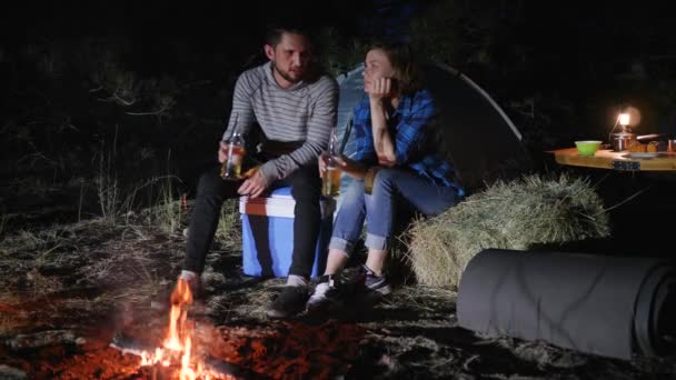 Mladý pár pití nápoje a dělat cinknutí sklenice v blízkosti ohně v nočním lese, milenci pít alkohol — Stock video