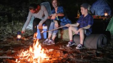 Kamp, anne-oğul ve baba ellerinde gaz lambası, ateşin yanındaki aletin üzerinde fotoğraflanmış, anne-baba ve çocuk.