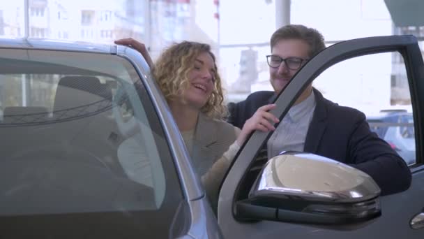 Auto kopen, gelukkig paar in de liefde voertuig eigenaren verrukking kopen en tonen sleutels in de auto sales center — Stockvideo
