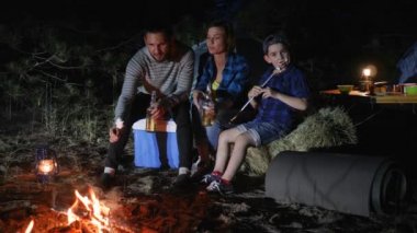 Hafta sonu ormanda aile gezisi, ormanlık alanda Amerikan ailesinin seyahat kampı, aileler bira içer ve çocuklar zephyr yer.