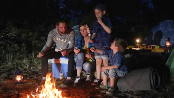Mama en papa met kinderen rusten uit naar de camping en roosteren zephyr op kampvuur, ouders met kinderen broil marshmallow — Stockvideo