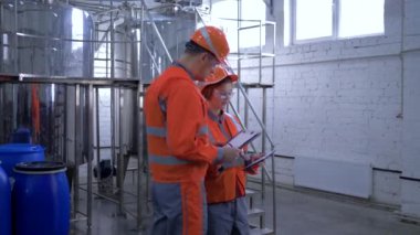 gender equality at heavy industry, smiling woman with male factory specialist in hard hats shake hands while walk through plant and discuss new project and making calculated engineering decisions