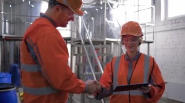 gender equality at work, Factory engineers Male and Female in Hard Hats Discuss New Project and Using Tablet Computer and shake hands