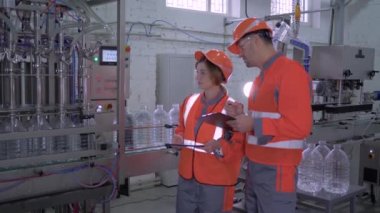 Miğfer ve tulum giymiş kadın ve erkek işçilerin portresi. Sıkı çalışma sırasında ellerinde tabletlerle taşıyorlar.